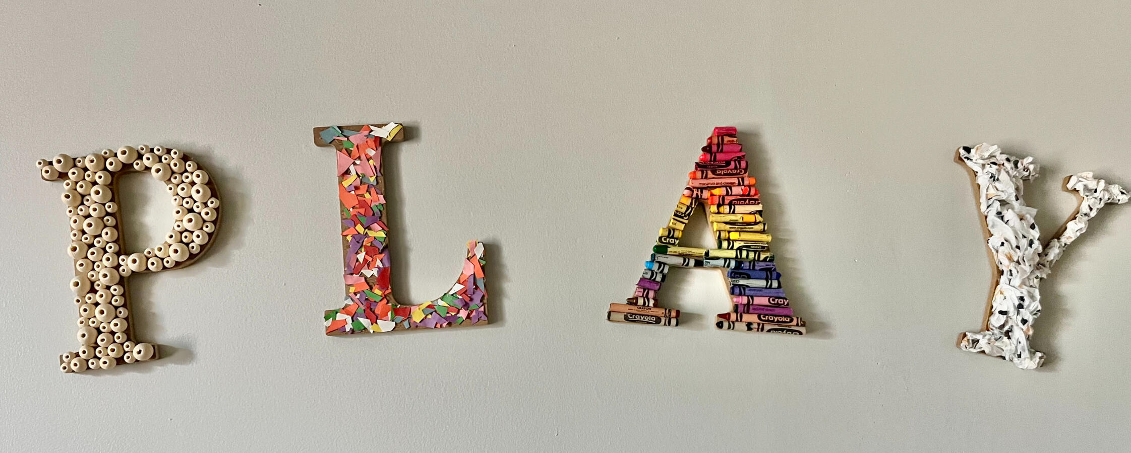 PLAY The word "PLAY" is spelled out on one of the Playroom walls in letters made of various, colorful materials.